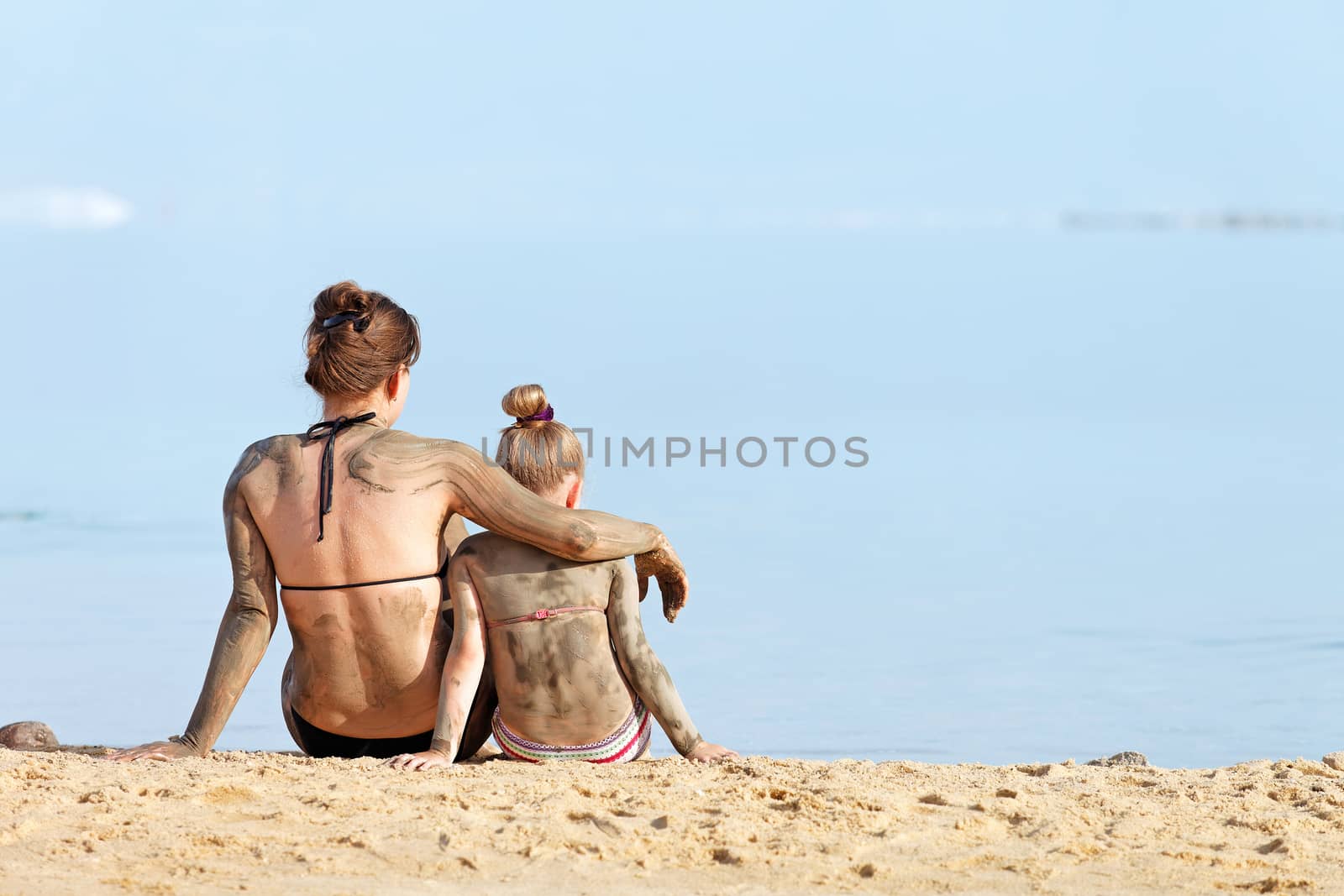 Mother and daughter in a bikini in the mud body treatment