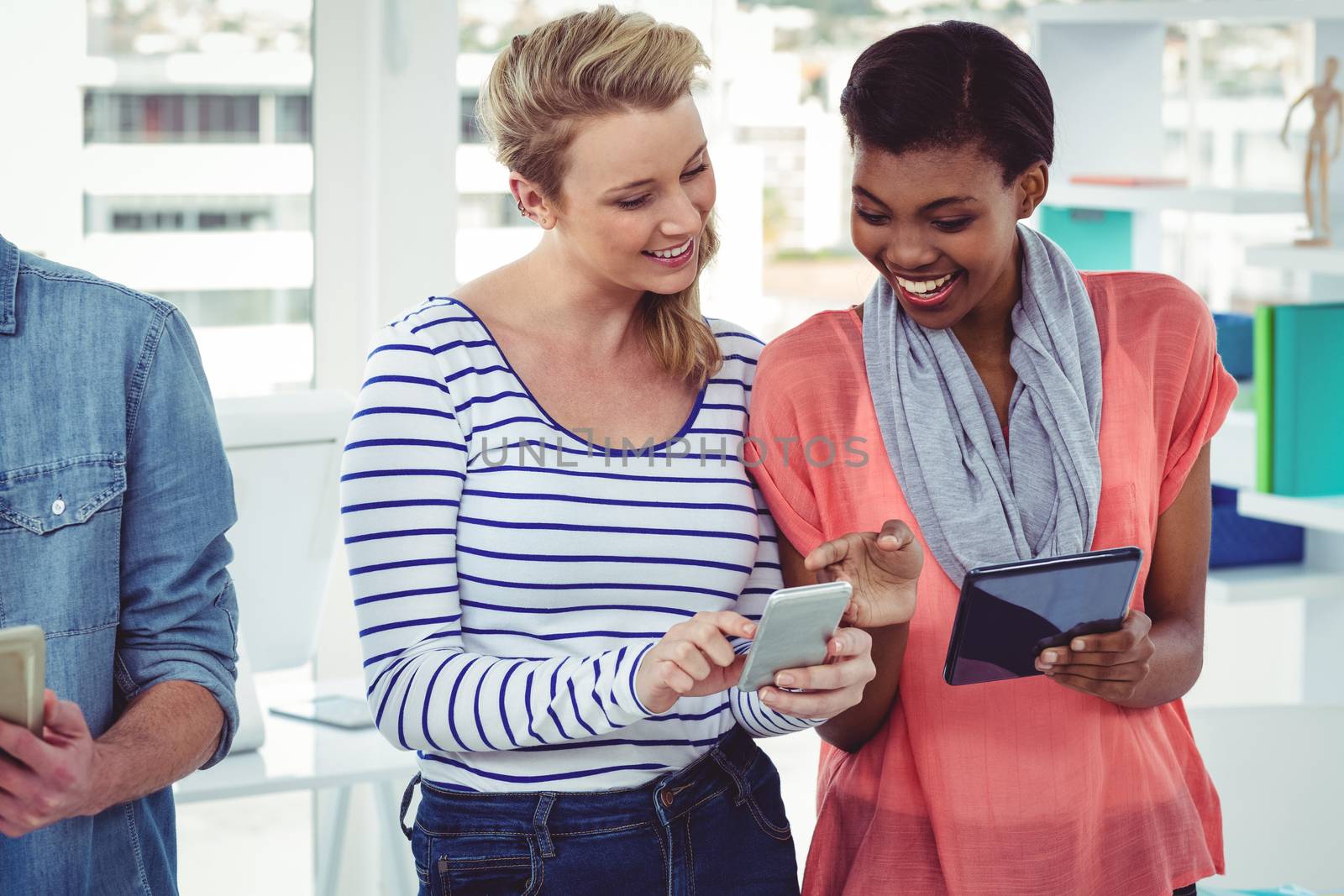 Smiling creative team standing in a line using technology in casual office