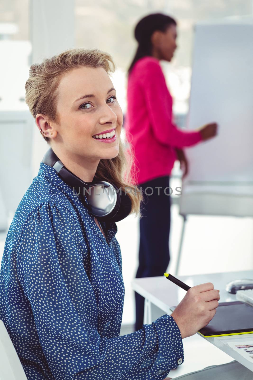 Graphic designer wearing headphones at desk in casual office