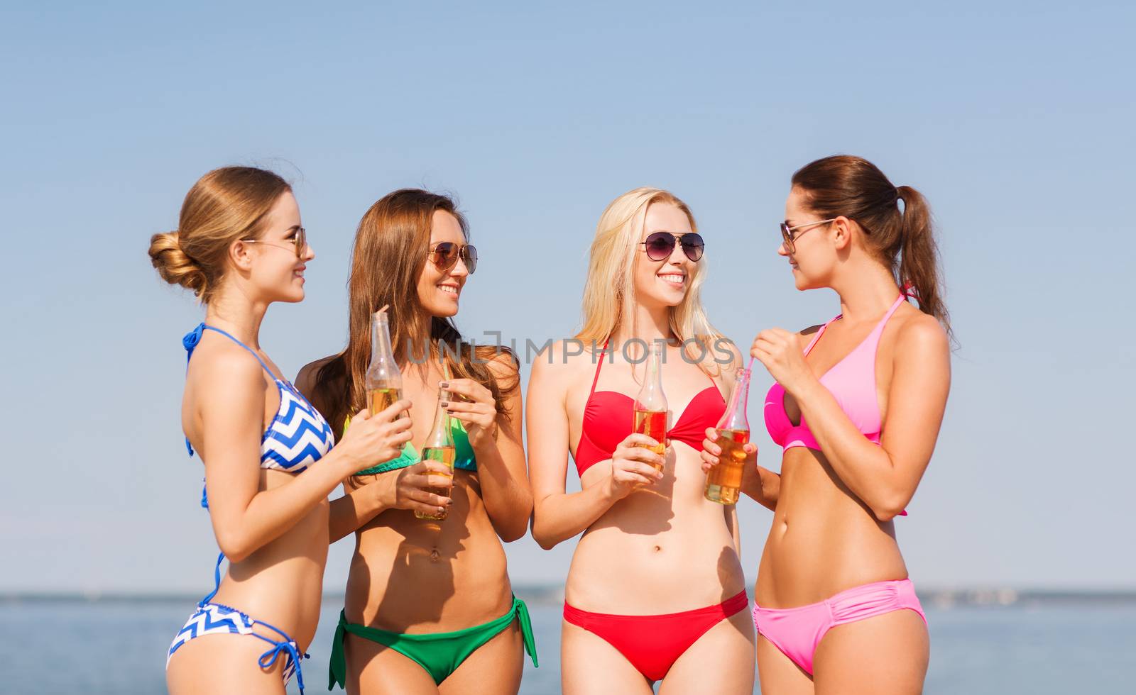 group of smiling young women drinking on beach by dolgachov