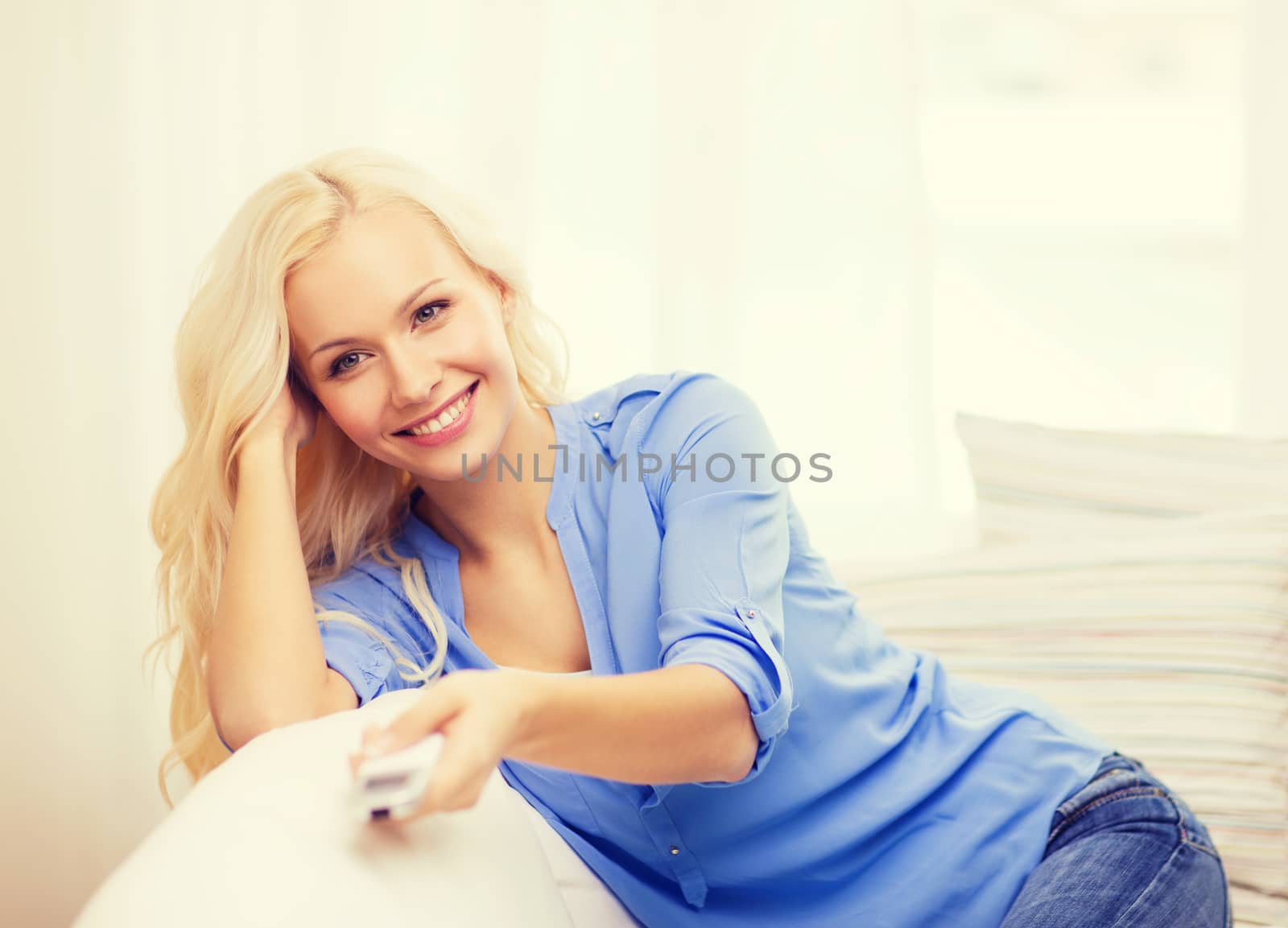 smiling young girl with tv remote control at home by dolgachov