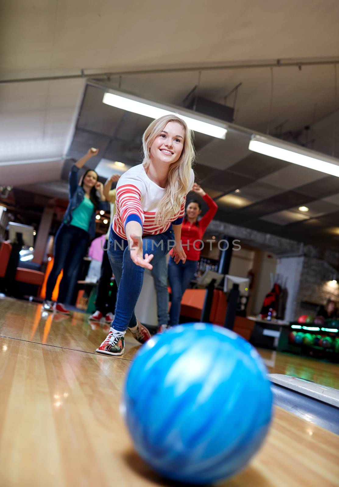 happy young woman throwing ball in bowling club by dolgachov