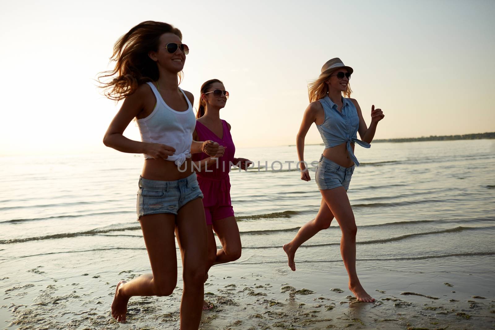 group of smiling women running on beach by dolgachov