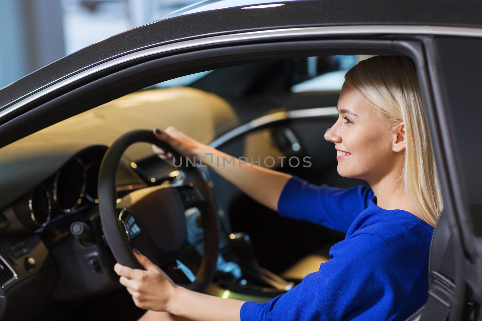 happy woman inside car in auto show or salon by dolgachov