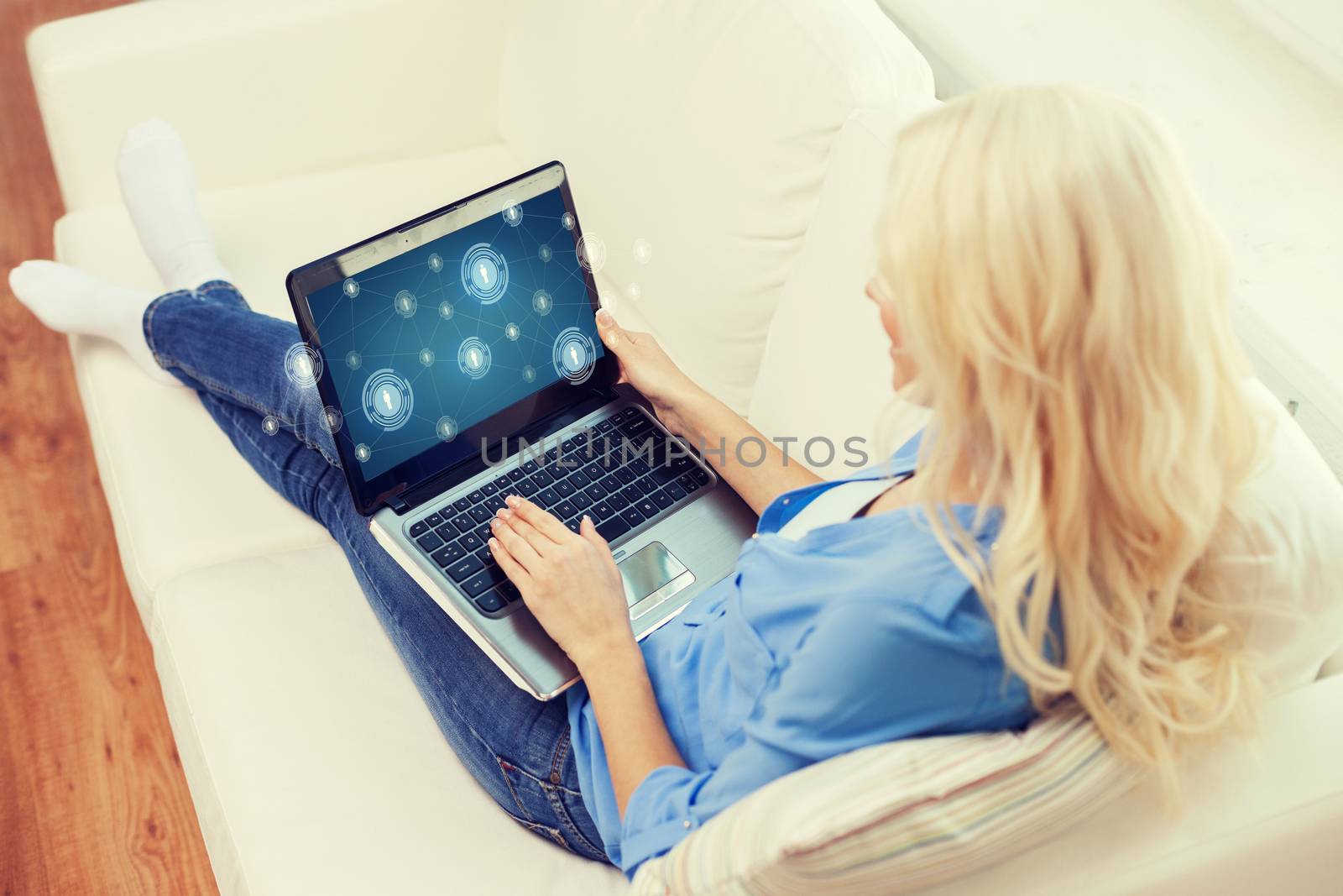 home, technology and internet concept - smiling woman with laptop computer sitting on couch at home