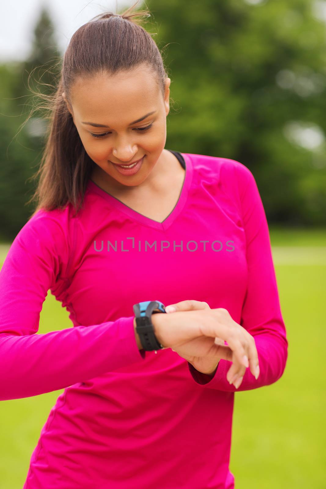 smiling young woman with heart rate watch by dolgachov