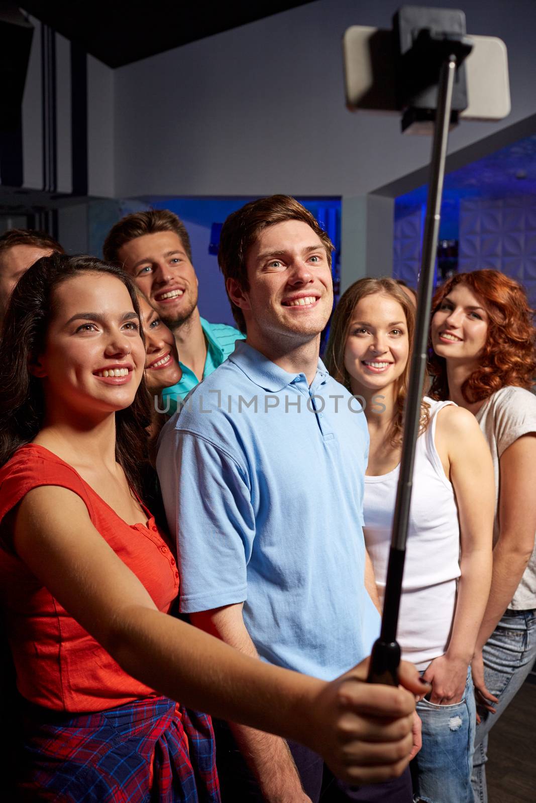 friends with smartphone taking selfie in club by dolgachov