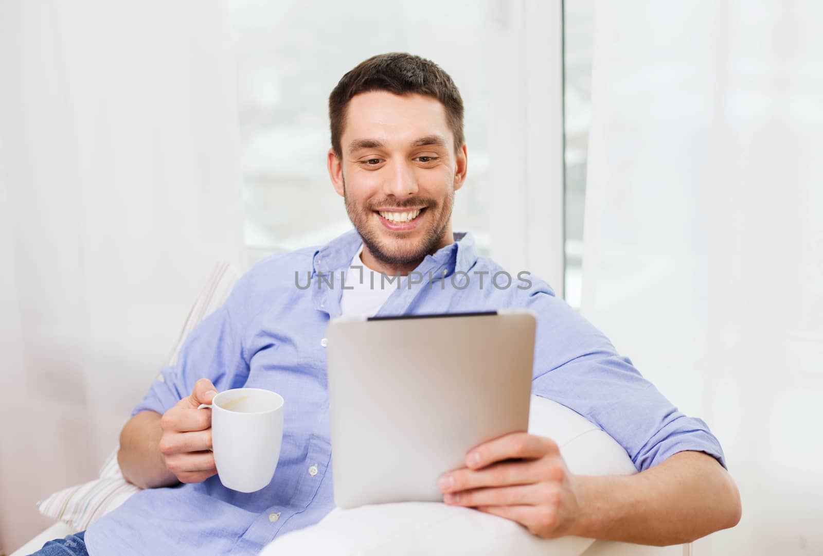 technology, people and leisure concept - handsome man with tablet pc computer and cup drinking coffee or tea at home