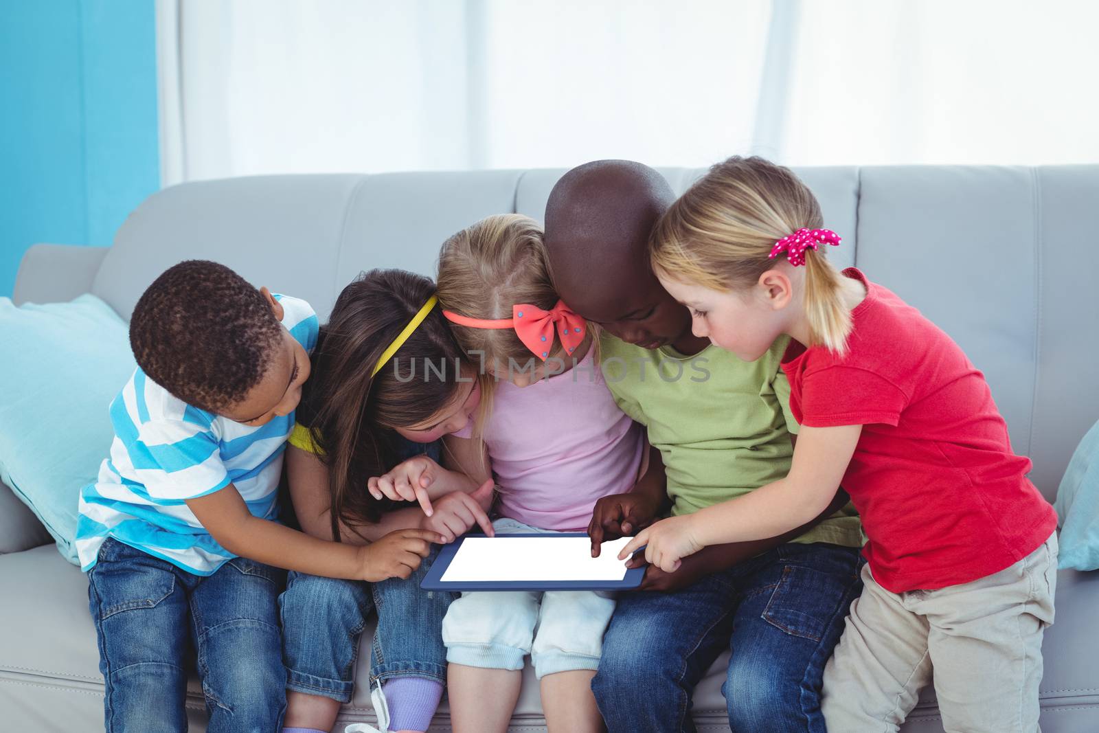 Happy kids using technology while sitting by Wavebreakmedia