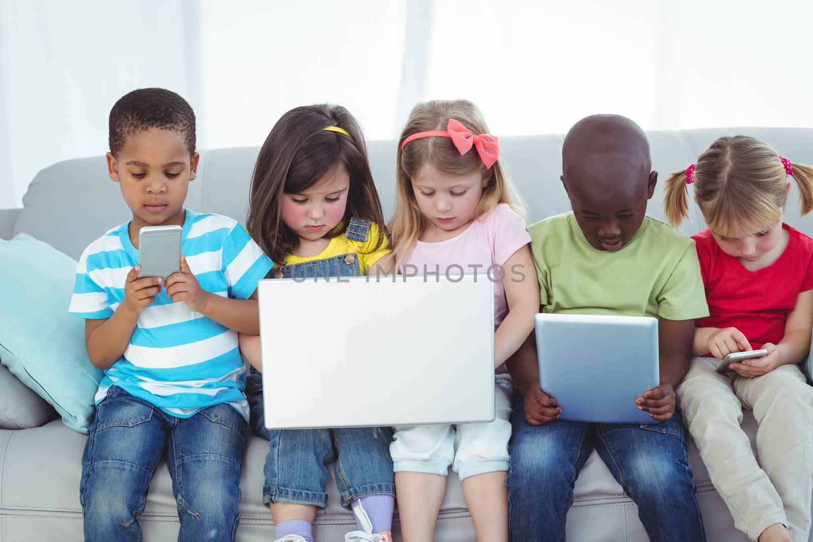 Happy kids using technology while sitting by Wavebreakmedia