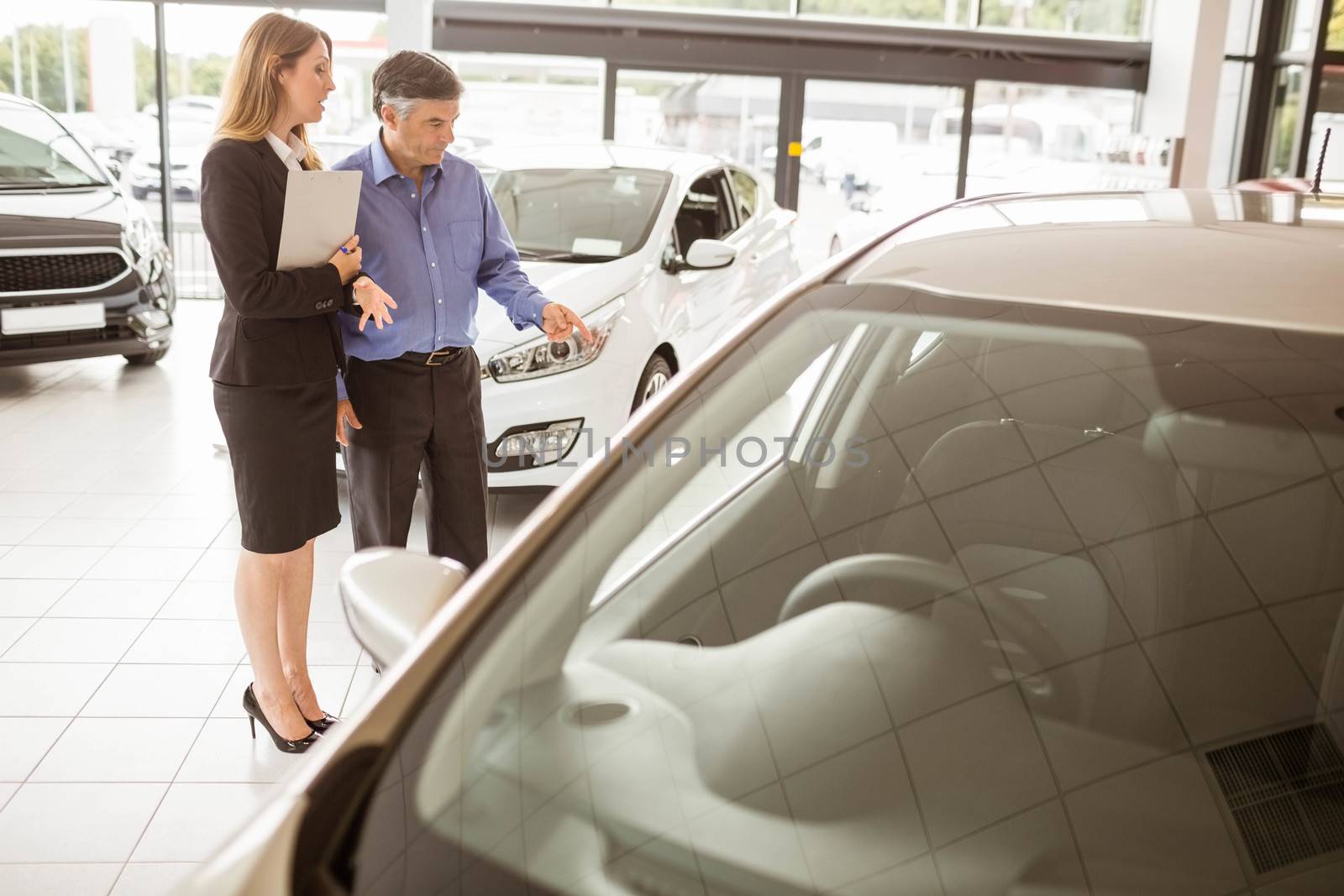 A man showing a car to the saleswoman at new car showroom