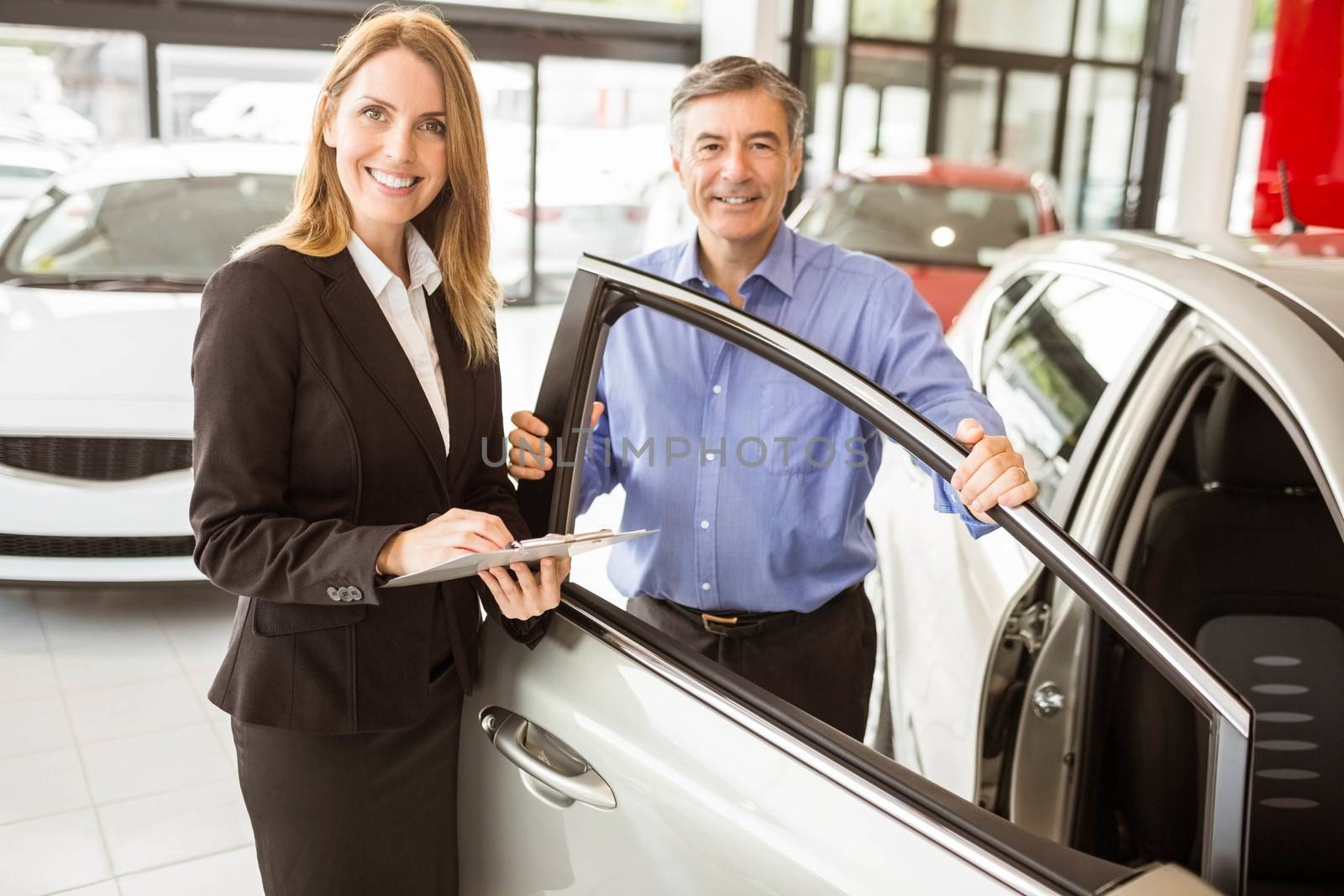 Businesswoman showing something to a man at new car showroom
