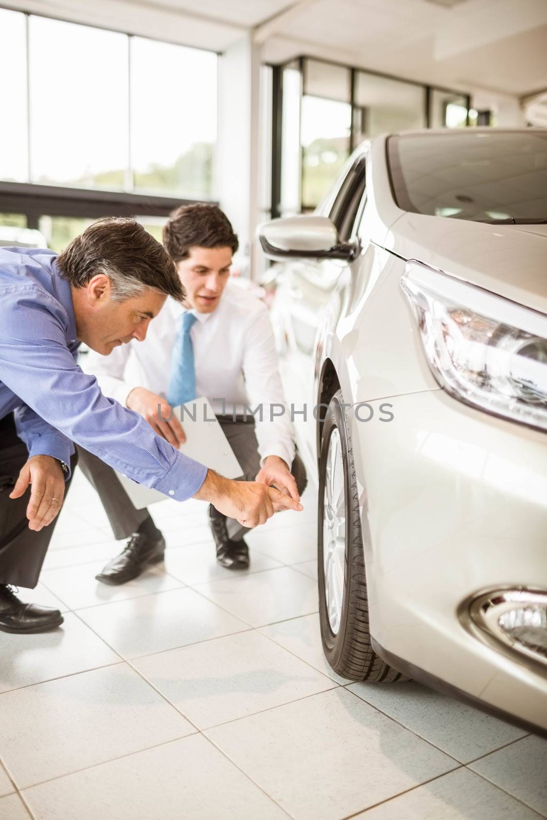Salesman showing somethings to a man at new car showroom