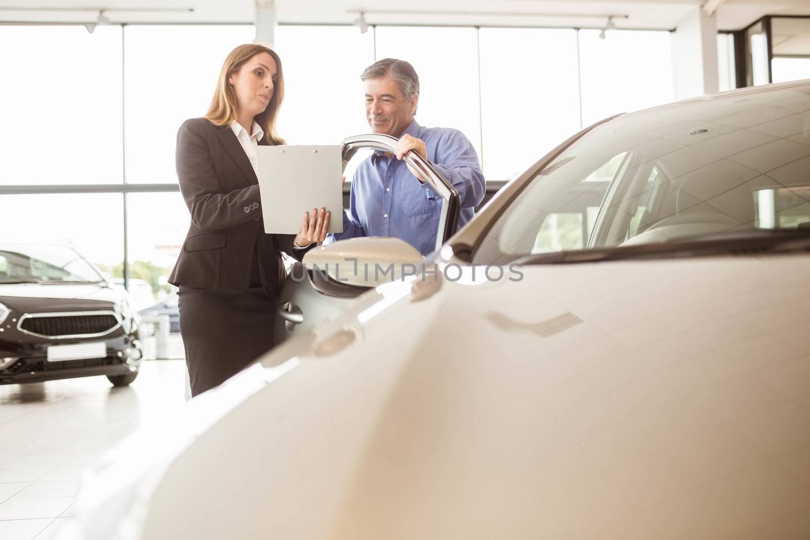 Smiling businesswoman undersign a car contract at new car showroom