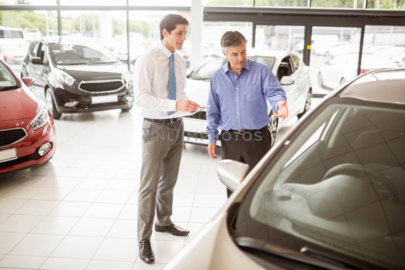 A man showing a car to the salesman by Wavebreakmedia
