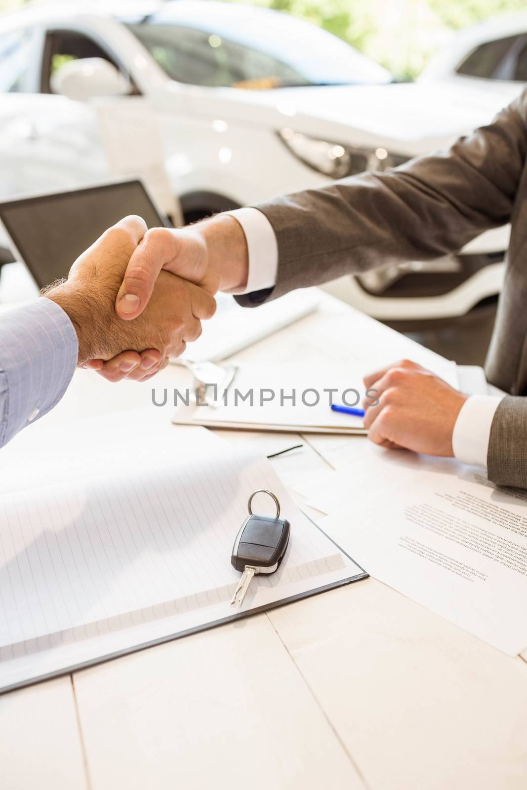 Salesman shaking a customer hand at new car showroom