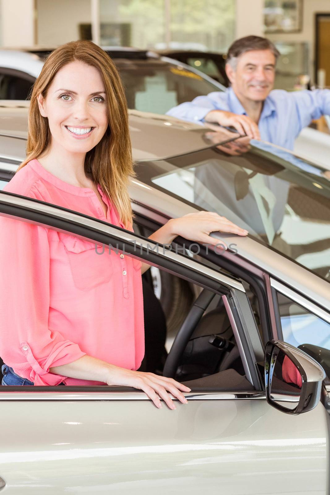 Smiling couple leaning on car at news car showroom