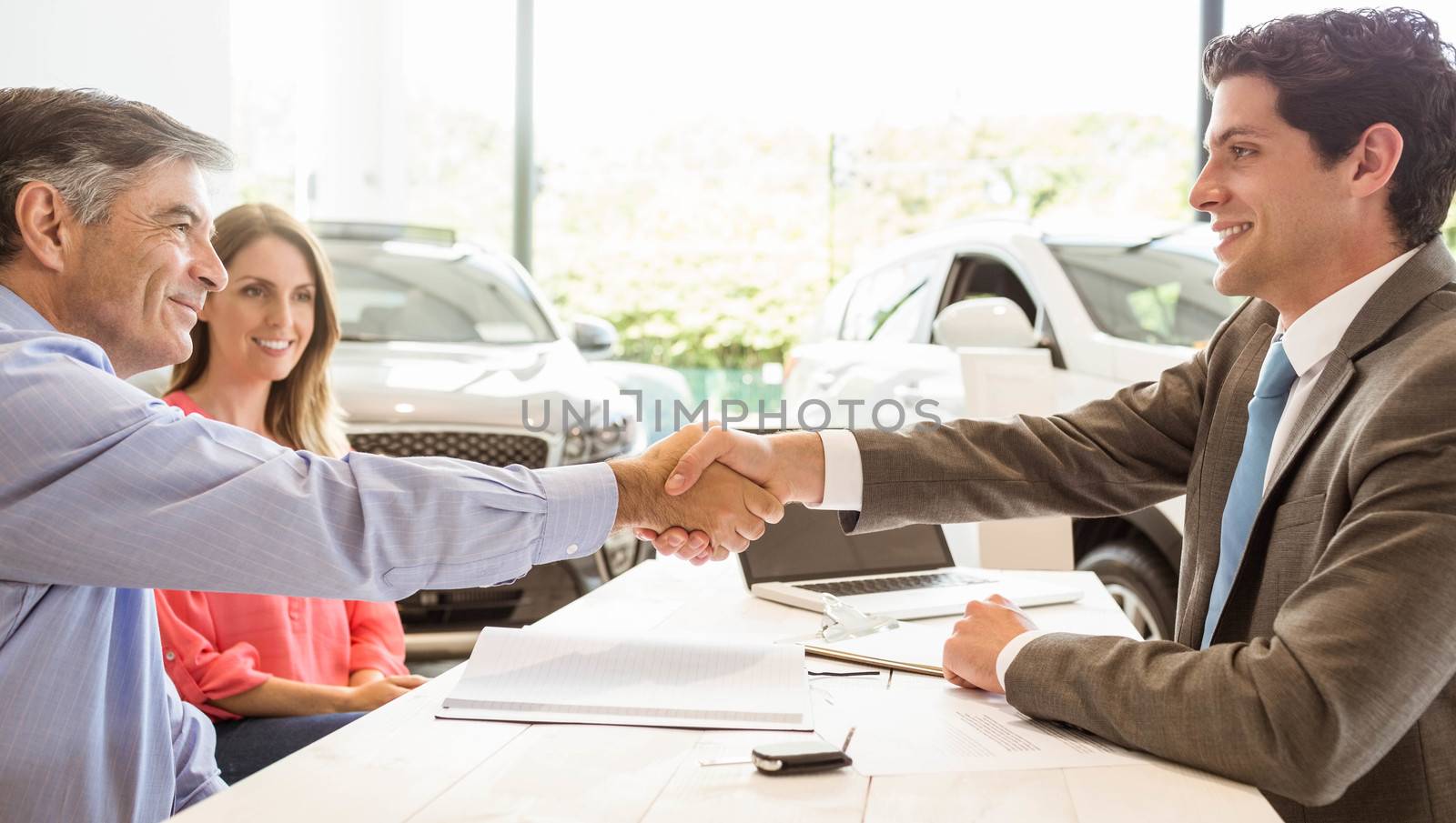 Smiling couple buying a new car by Wavebreakmedia