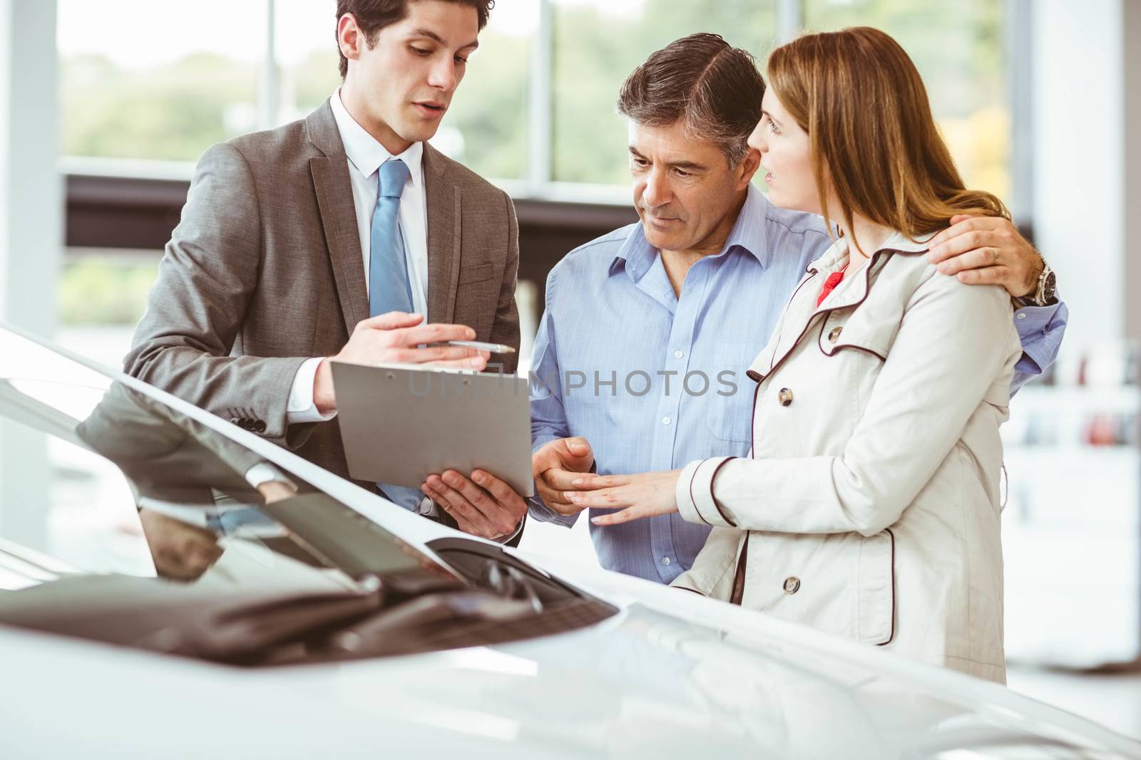 Smiling businessman presenting a car at new car showroom