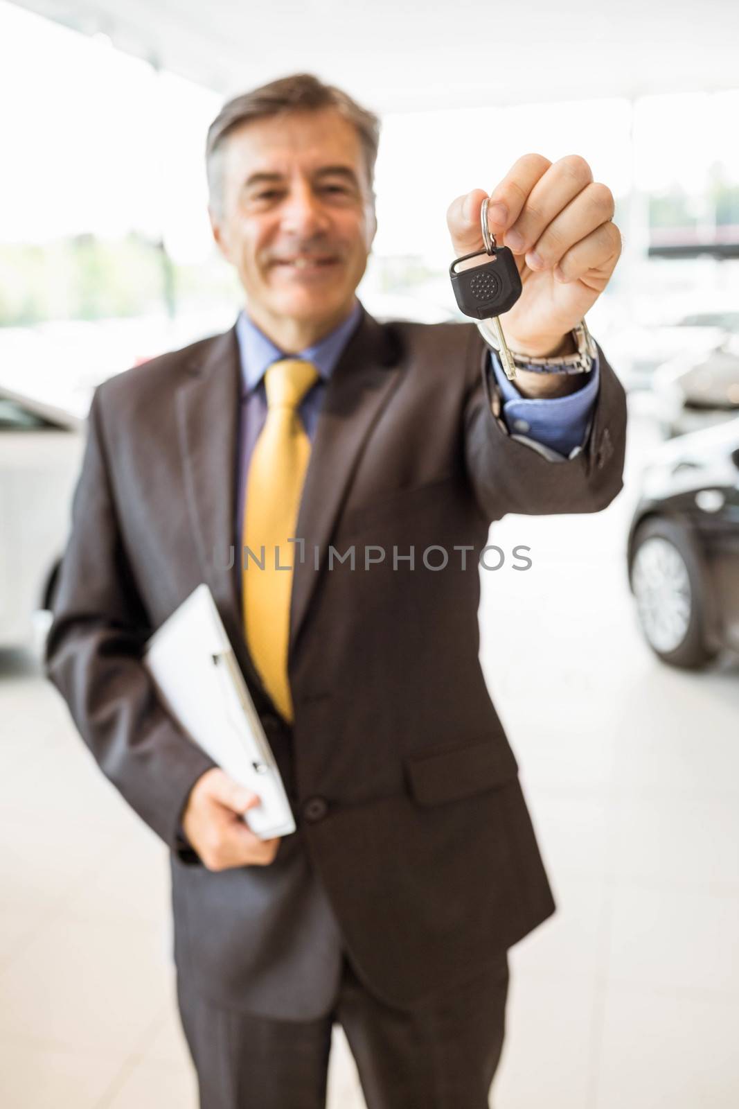 Male driver showing a key after buying a new car by Wavebreakmedia