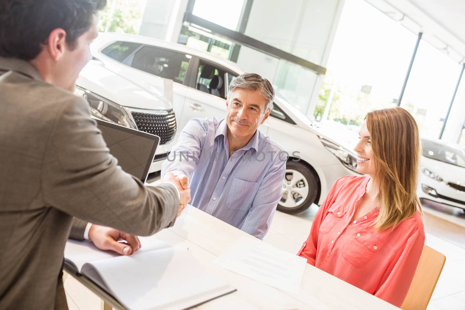 Smiling couple buying a new car at new car showroom