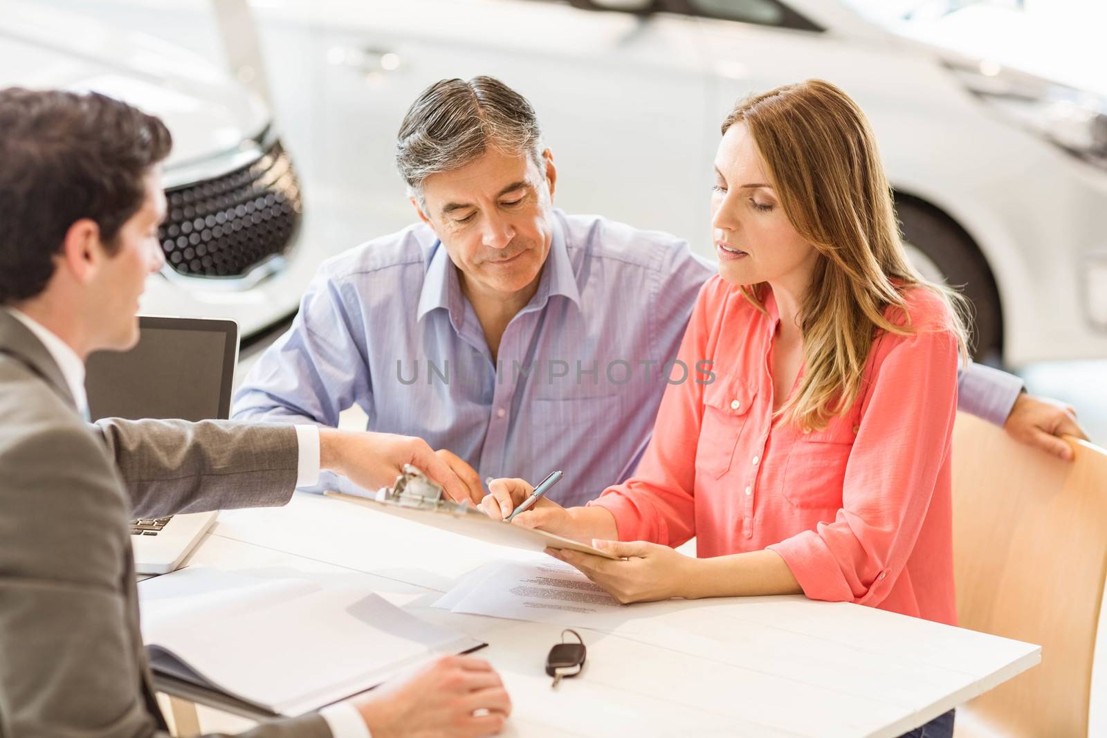 Smiling couple buying a new car at new car showroom