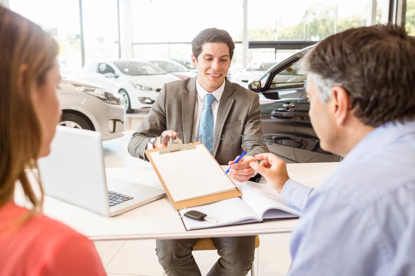 Smiling couple buying a new car by Wavebreakmedia