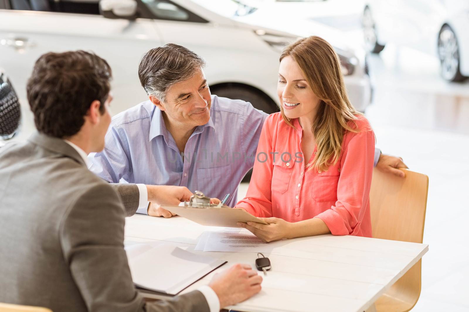 Smiling couple buying a new car by Wavebreakmedia