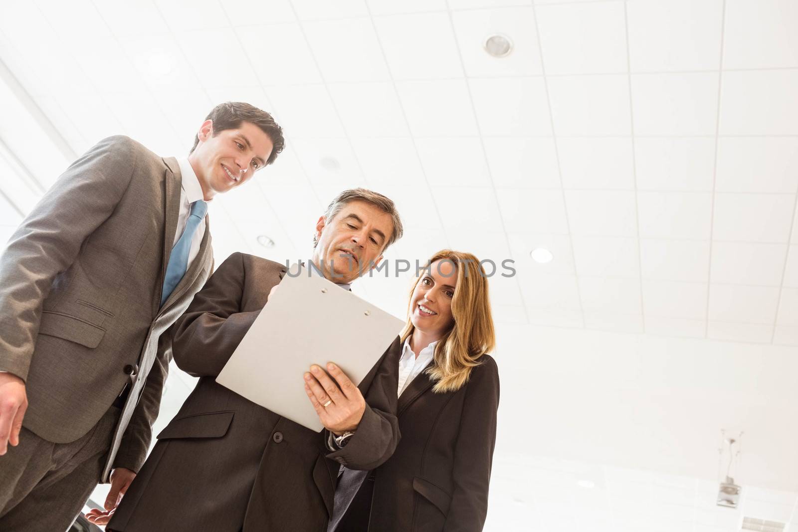 Group of smiling business team standing together at new car showroom