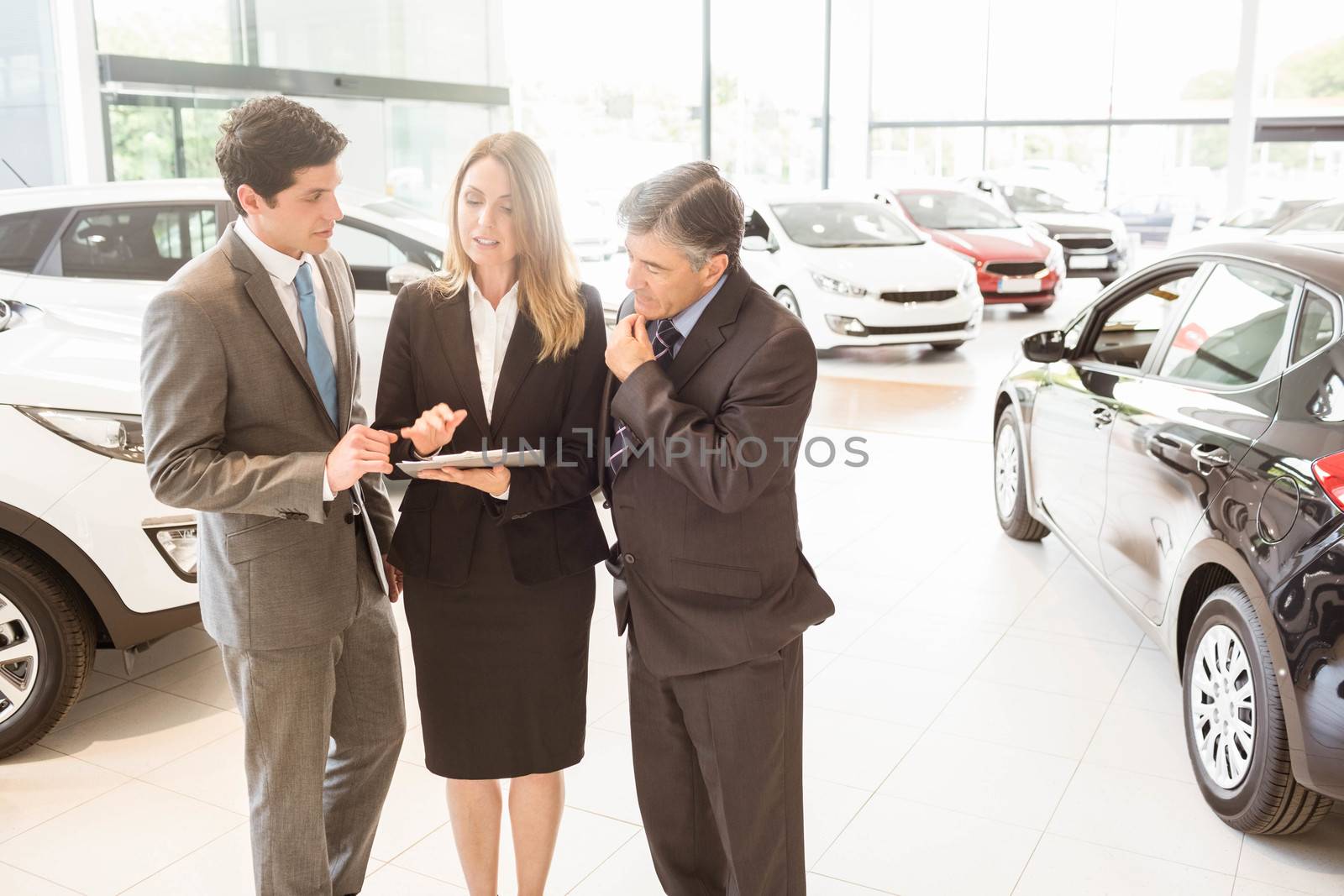 Sales team look at a clipboard at new car showroom