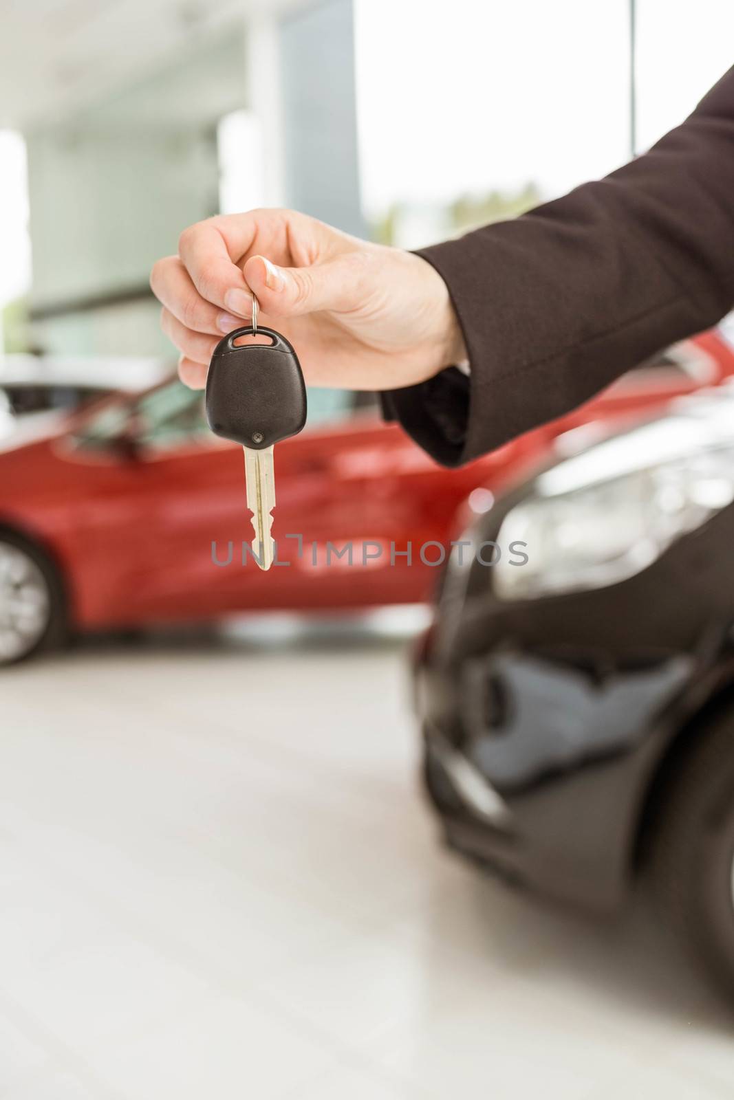 Saleswoman holding a car key at new car showroom