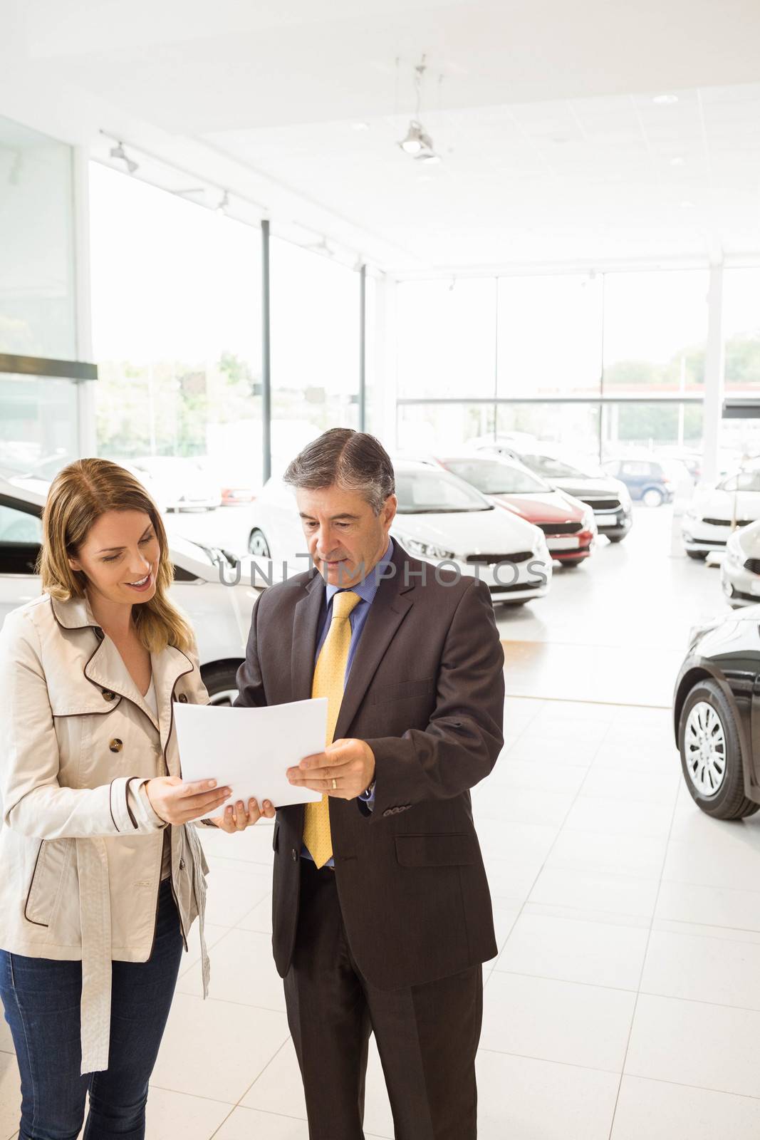 Salesman explaining the contract to a client at new car showroom