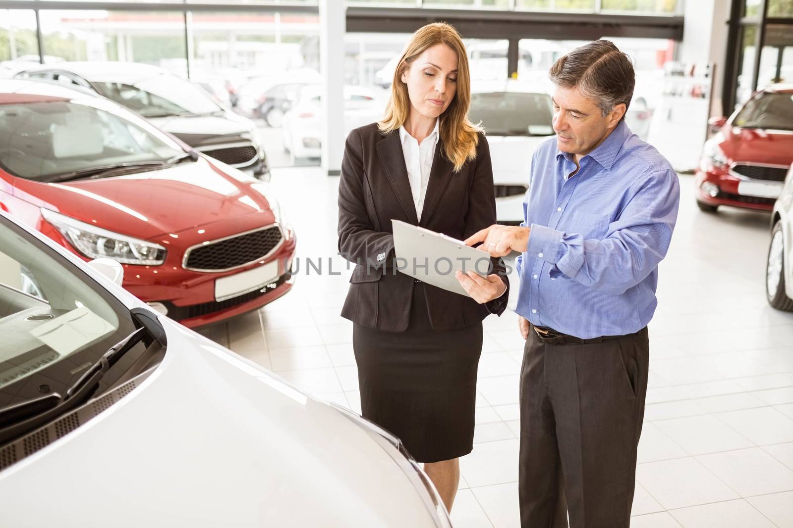  Focused businessman undersign a car contract at new car showroom