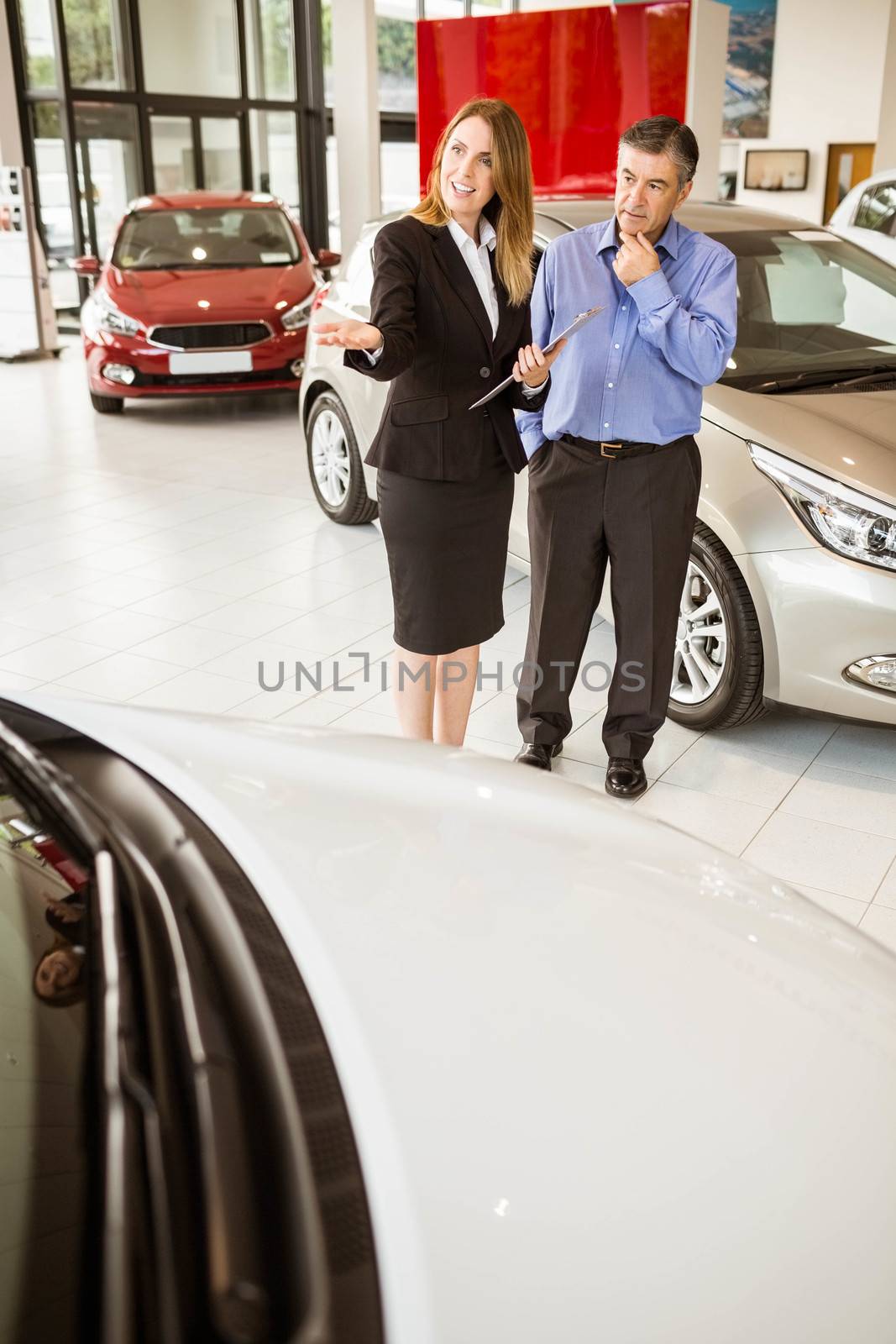 Smiling businesswoman showing car to customer  by Wavebreakmedia