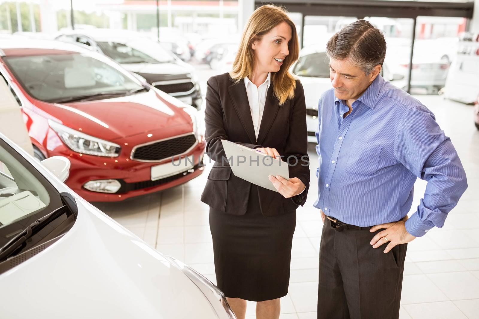  Smiling businessman undersign a car contract at new car showroom