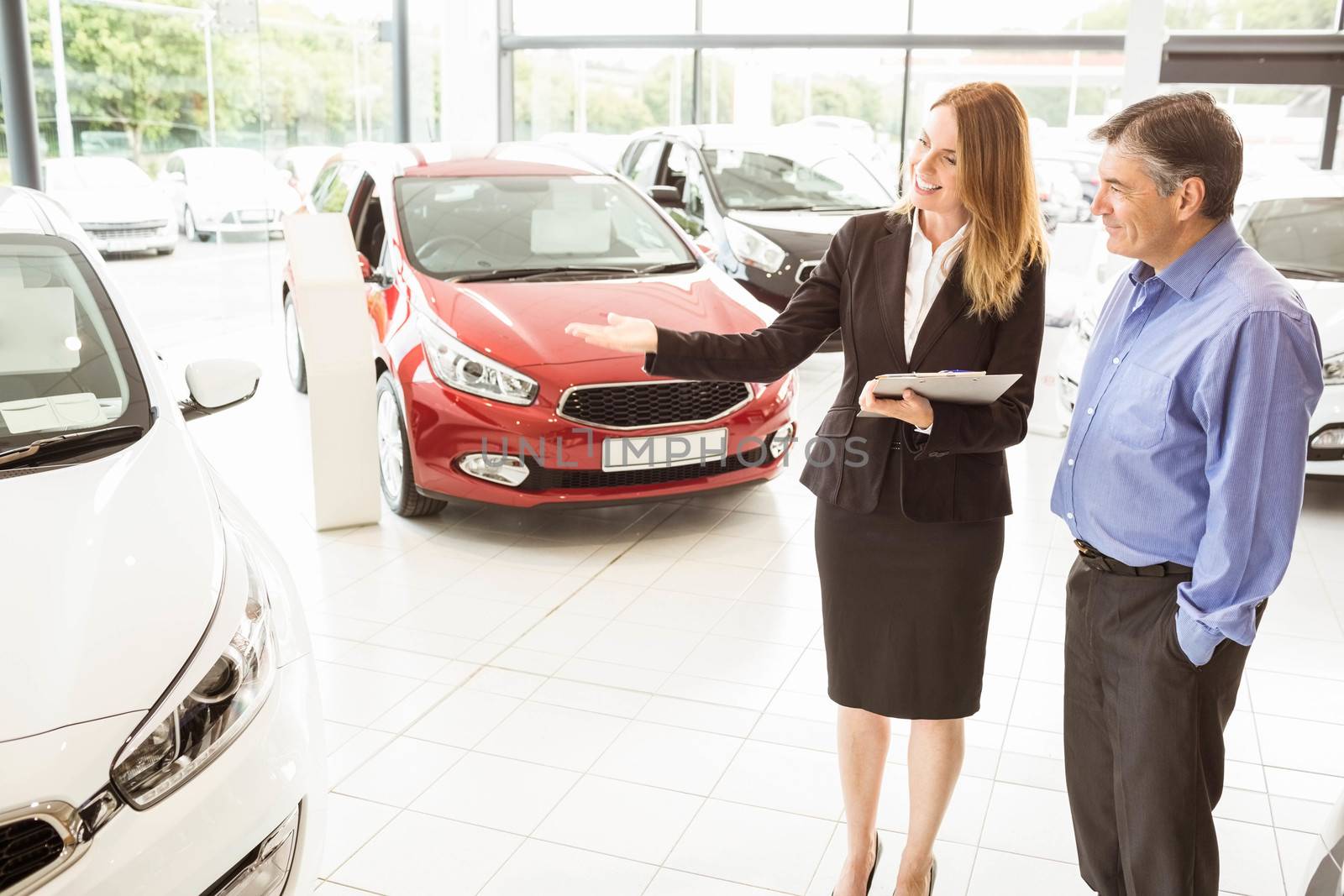 Smiling businesswoman showing car to customer  by Wavebreakmedia