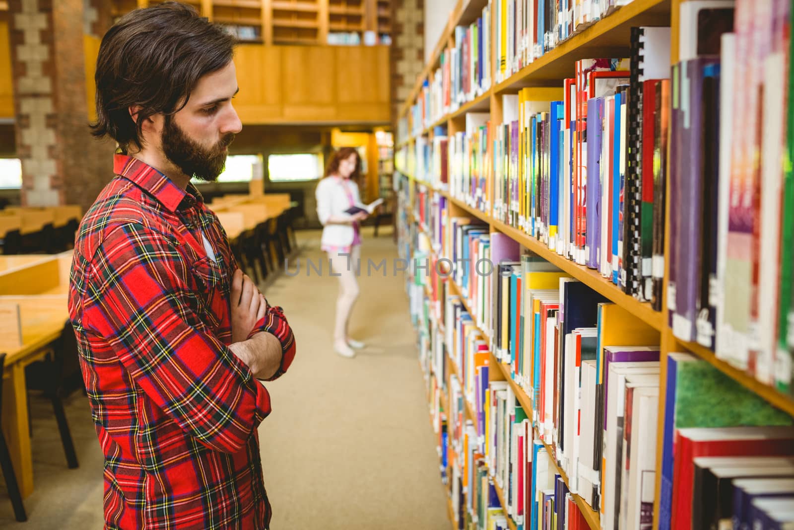 Hipster student picking a book in library at the university