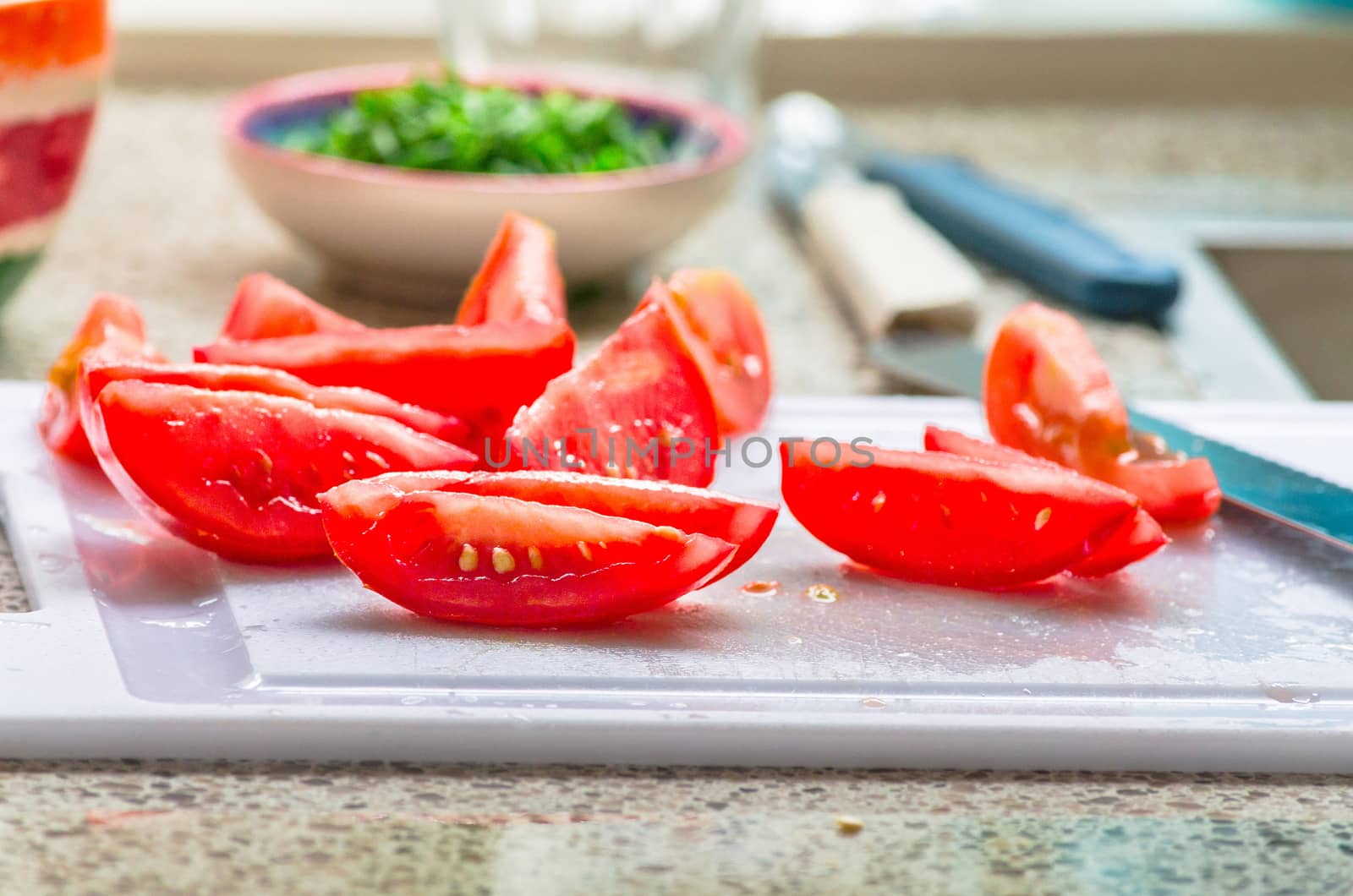 Fresh sliced tomato pieces, in the background a small bowl of freshly chopped chives.