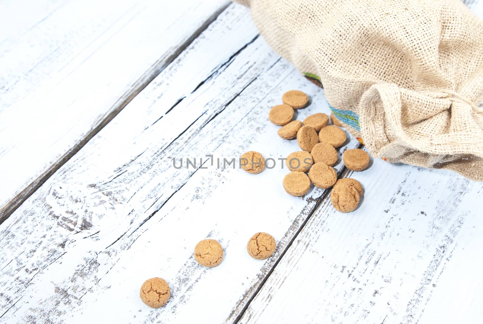 Dutch candy pepernoot with jute bag on white blue wooden background