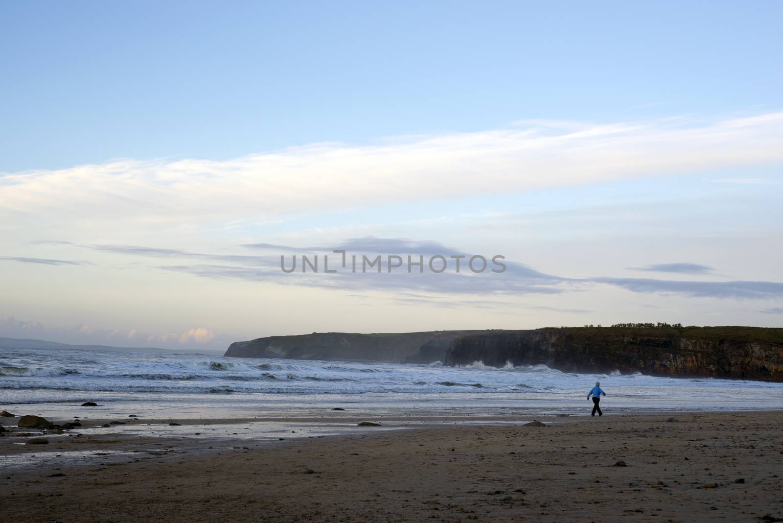 woman walking at rocky cold beach by morrbyte