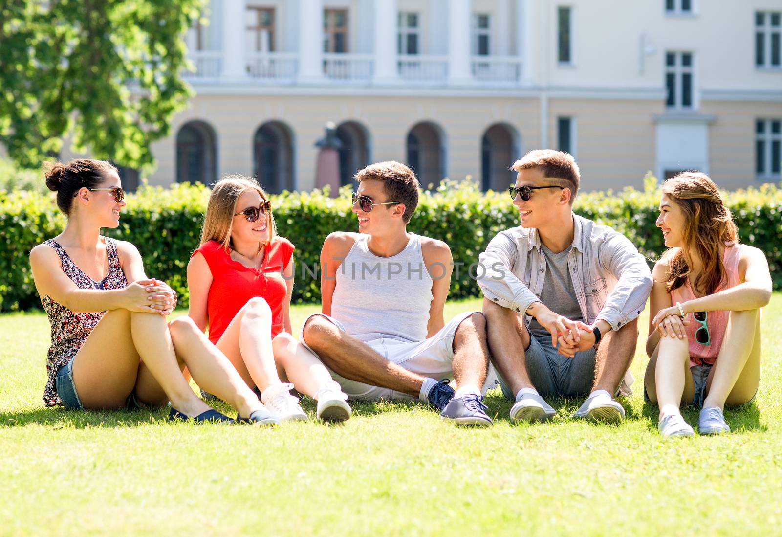 group of smiling friends outdoors sitting on grass by dolgachov