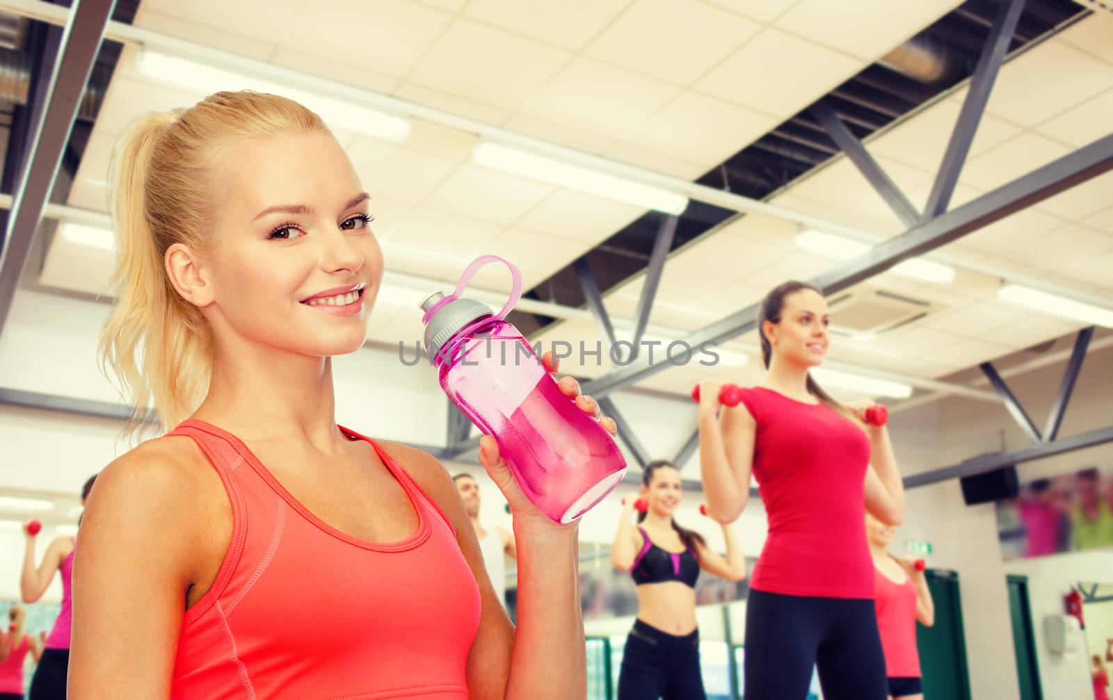 smiling sporty woman with water bottle by dolgachov