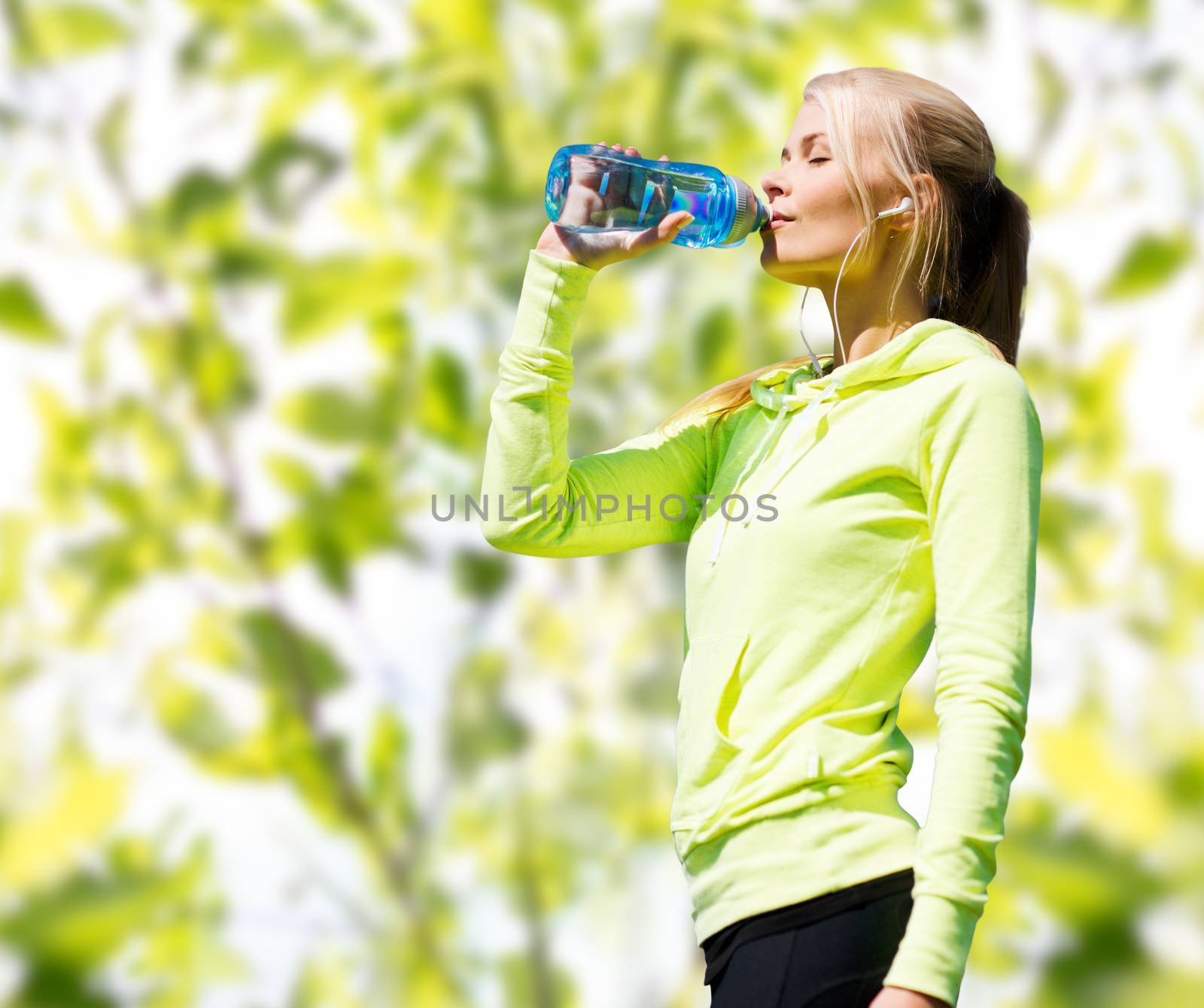 fitness, sport, people and thirst concept - happy woman drinking bottle water after doing sports over green tree leaves background