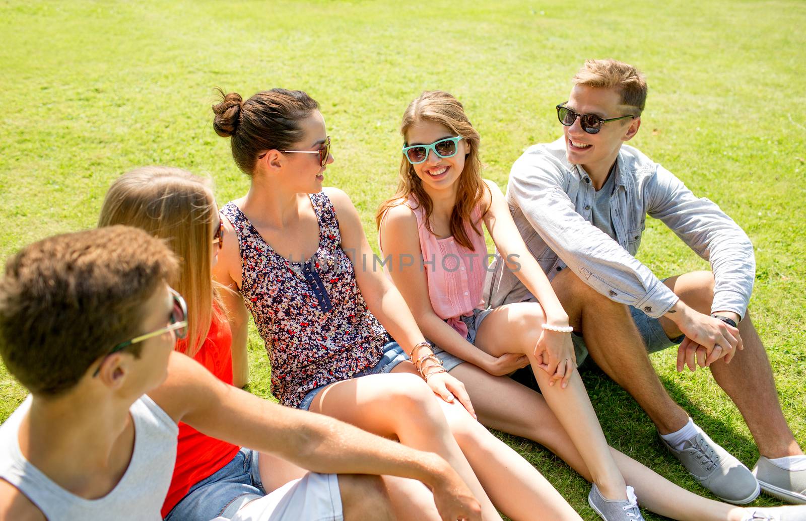 group of smiling friends outdoors sitting in park by dolgachov