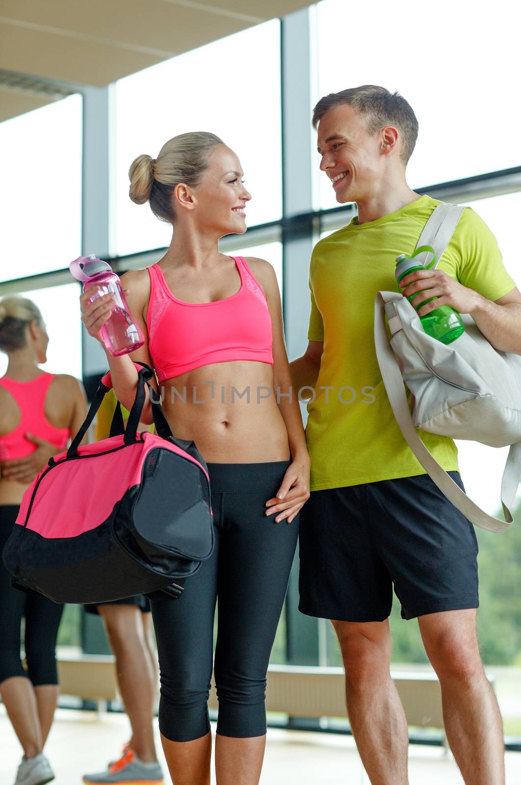 smiling couple with water bottles in gym by dolgachov
