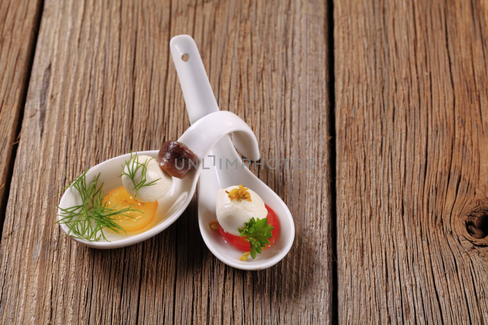 Mozzarella cheese snacks on porcelain spoons - closeup
