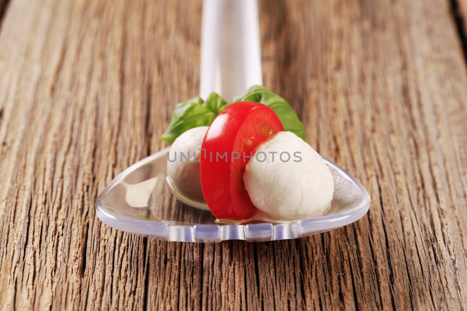 Mozzarella cheese balls and tomato on a salad spoon