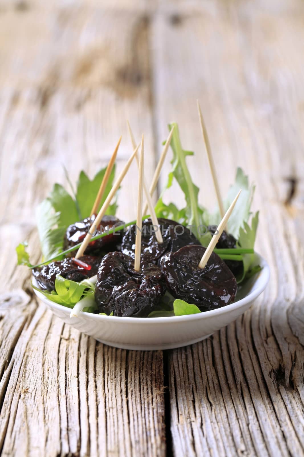 Bowl of prunes and salad greens - closeup
