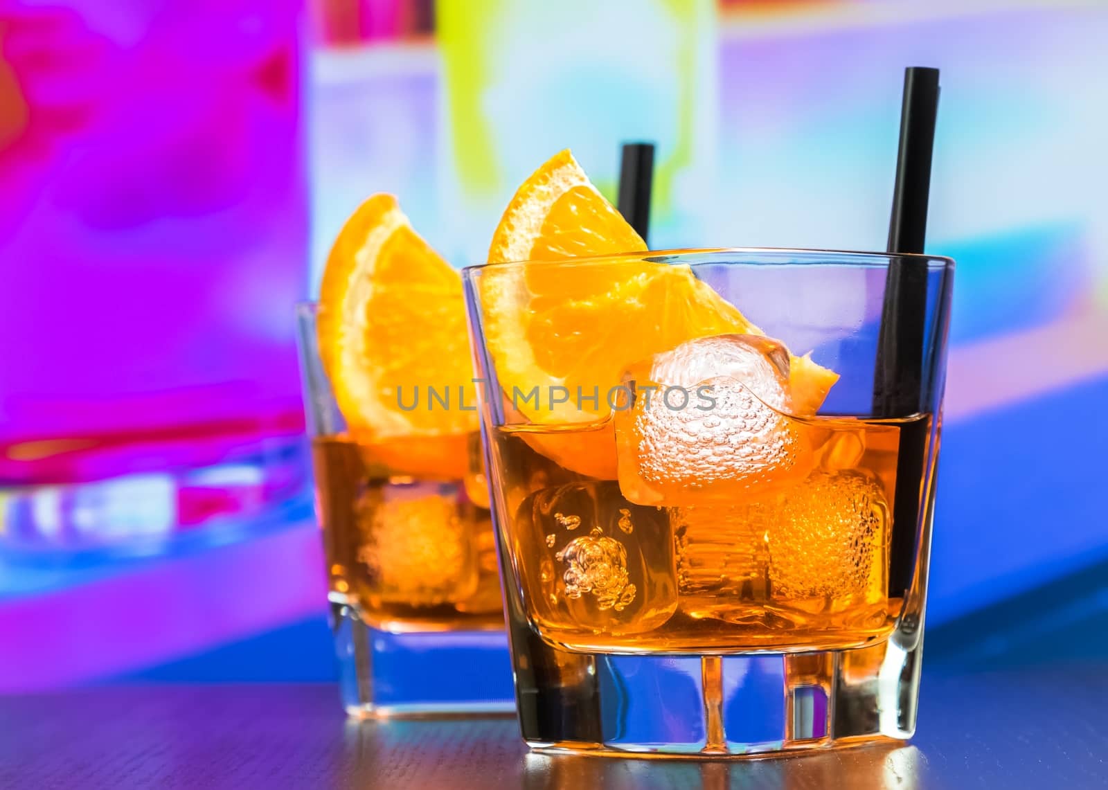 two glasses of spritz aperitif aperol cocktail with orange slices and ice cubes on bar table, disco atmosphere background, lounge bar concept