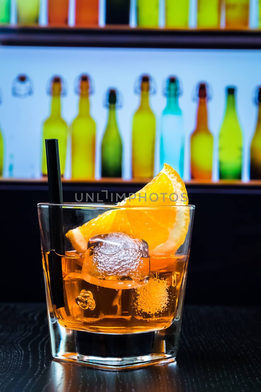 glass of spritz aperitif aperol cocktail with orange slices and ice cubes on bar table, disco lounge bar atmosphere background, lounge bar concept